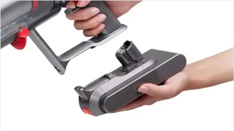 Charged battery being clicked into the handle of the Dyson V15 Total Clean vacuum cleaner.